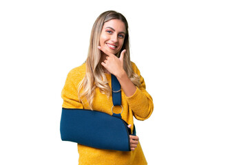 Young Uruguayan woman with broken arm and wearing a sling over isolated background happy and smiling