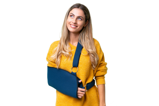 Young Uruguayan woman with broken arm and wearing a sling over isolated background thinking an idea while looking up