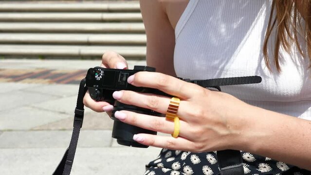 Close-up of a girl's hands holding a camera and looking through the photos on it.
