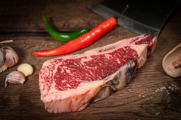 Raw beef steak with spices on a dark slate, stone or concrete background. Top view with copy space.