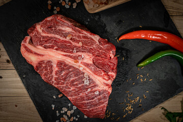 raw cowboy steak with seasonings on wooden background, prime rib eye on bone, top view