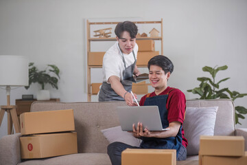 Fototapeta na wymiar A cheerful young Asian gay couple checks their online product orders on a tablet and celebrates their orders success while working at home together. LGBT couple, e-commerce, online shop, online seller
