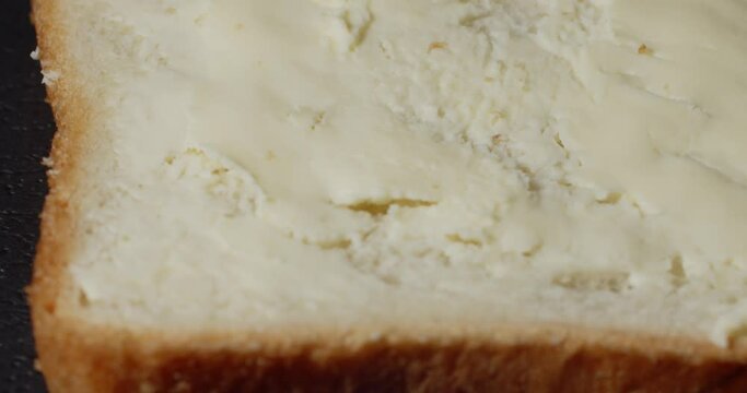 a slice of bread spins. butter is applied to it with a knife
