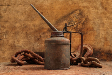 A close up on an old oil can covered with rust with a wooden background 