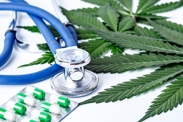 Medical marijuana and stethoscope. Green leaves of cannabis,pills and cbd oil over medical...