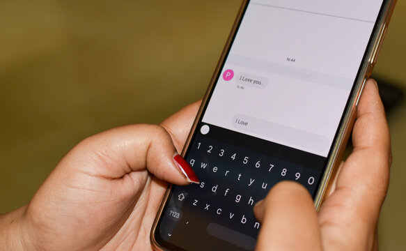 Sending I love you a text message with a mobile phone. Online dating, texting or catfishing concept. Romance fraud, scam or deceit with a smartphone. Fake profile. Internet safety.