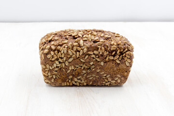 rye bread with sunflower seeds loaf on a white wooden table.