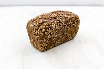 rye bread with sunflower seeds loaf on a white wooden table.