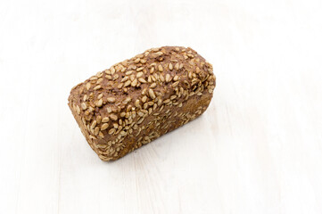 rye bread with sunflower seeds loaf on a white wooden table.