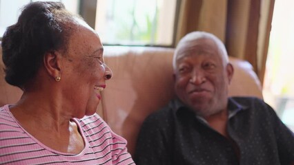 Happy senior relationship interaction. An elderly black Brazilian husband and wife laughing and smiling together on couch