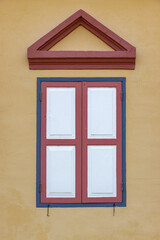 A window with a shutter on the facade of a historic building, Thailand