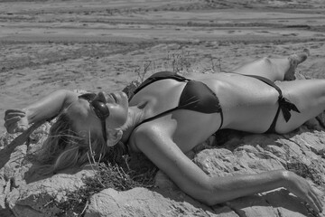 Woman in bikini lying on sand at beach - obrazy, fototapety, plakaty