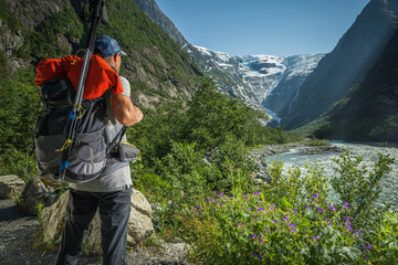 Fototapeta na wymiar Caucasian Hiker Taking Quick Look on a Scenic Kjenndal Glacier Valley