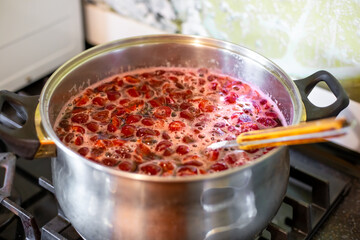 Seedless cherry jam is cooked in a large saucepan on the stove. Preservation of fruits and berries