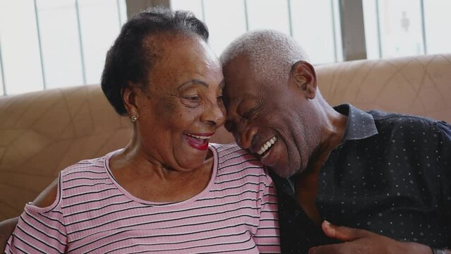 Loving relationship at old age, a black senior husband leaning on wife's forehead smiling. Happy elderly married couple interaction