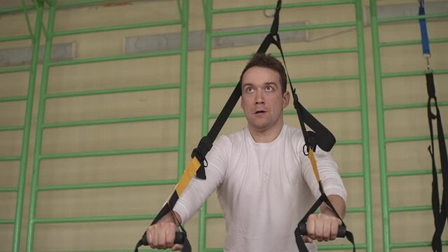 man in a white t-shirt. workout with fitness loops in the gym. close-up. man is engaged in the gym. High quality Full HD video recording 