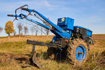 agricultural machinery in the field,in autumn, there is a walk-behind tractor with a plow in the field