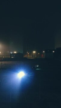 The man with flashlight is walking through empty parking lot