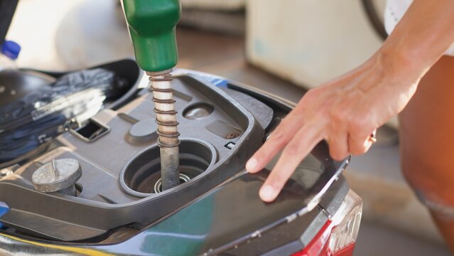 close-up image of a young woman refueling a scooter