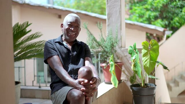 One joyful black Brazilian senior man smiling at camera at home backyard. Older African American person with friendly charismatic expression