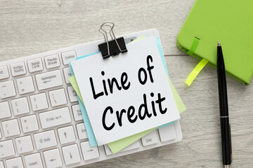 top view of text on sticker on white keyboard LINE OF CREDIT. Workplace close-up. Business concept