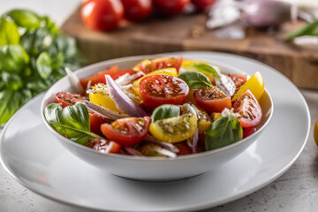 Tomato salad with red onion and olive oil is served in white bowl