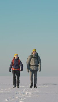 The couple of happy travelers walking through the snow field. slow motion