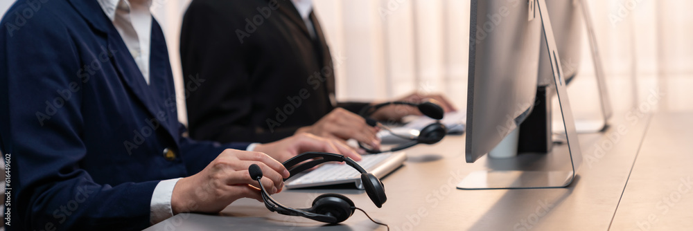 Aufkleber panorama focus hand holding headset on call center workspace desk with blur background of operator t