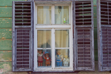 Vintage dolls in an old wooden window on the street of Sibiu. Transylvania. Romania
