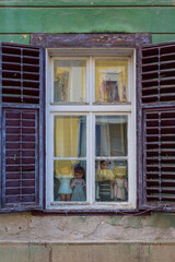 Fototapeta na wymiar Vintage dolls in an old wooden window on the street of Sibiu. Transylvania. Romania