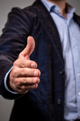 Hombre elegante dando la mano a cámara en expresión de saludo y acuerdo © Javier