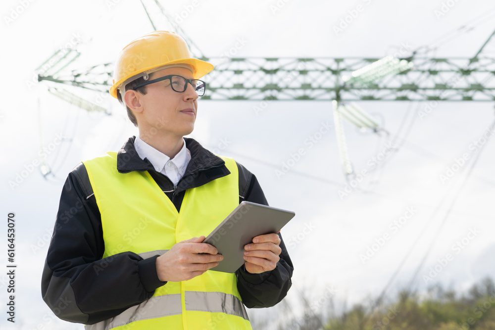 Poster Engineer with digital tablet on a background of power line tower..