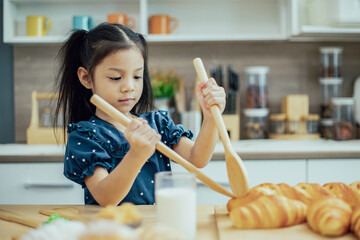 Asian little girl prepar bread with a glass of milk and many bakery in wooden tray for breakfast in the morning.