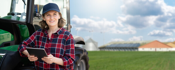 Woman farmer with a digital tablet on the background of an agricultural tractor