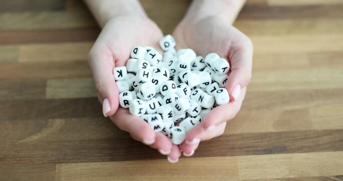 Hands hold and lot of white bones with English letters on table closeup. English language learning