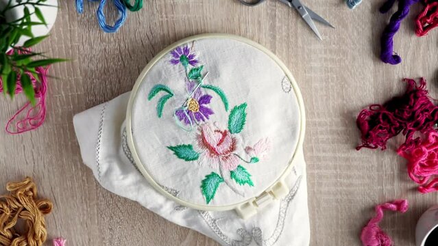 embroidery hoop with floral embroidery. floss threads around. top view.	