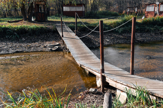 Broken wooden bridge over a canal with dirty water