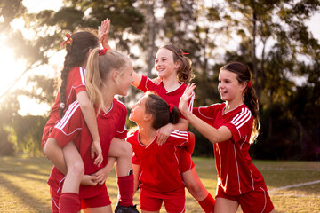 Happy football team of tween girls celebrating together