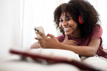 Portrait of a happy African American girl listening music on line with wireless headphones from a...