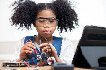 African American girls determined and serious to making and fixing electrical robot car and...
