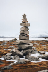 Fototapeta na wymiar A minimalist Inukshuk made of piled stones pointing the way across the Alaskan tundra. AI generative