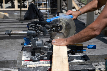 A man cutting a pice of wood with an electric saw