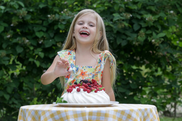 Adorable little girl in floral summer dress eating Pavlova cake