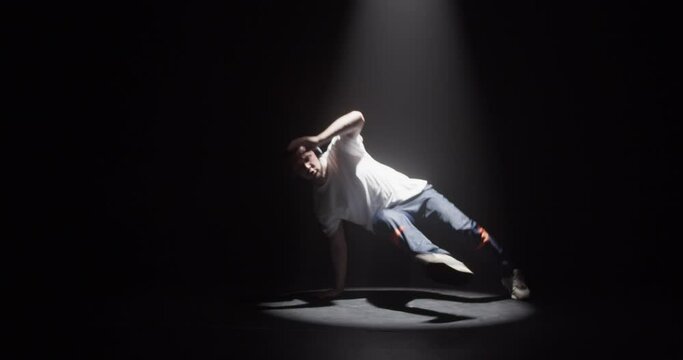Male dancer in spotlight dancing breakdance