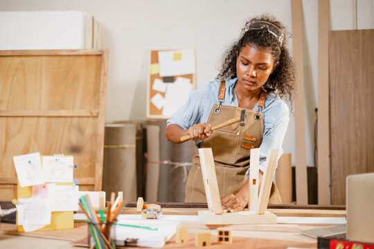 African Black Woman Carpenter Joiner Working Build Wooden Chair Handcraft Furniture In Wood Studio Workshop.