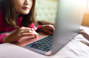 woman with laptop computer working and internet on her bed