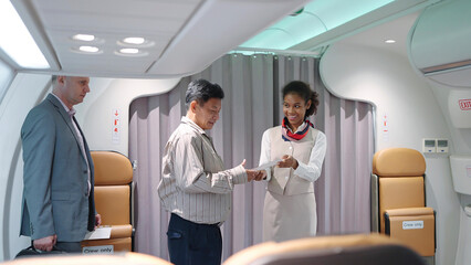 Young women flight attendant, stewardess in uniform standing in the airplane entrance smiled friendly and checking passenger's boarding pass and welcoming to the flight. Airline transportation