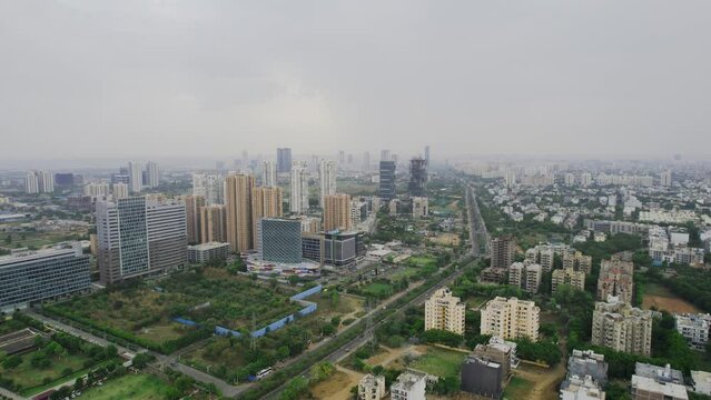 aerial drone shot flying forward rapidly over small residential houses to skyscraper towers with offices and shopping centers fading in fog in city of gurgaon