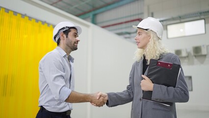 Happy engineers man and women colleague having shaking hands together of success working at industry manufacturing factory. Teamwork concept