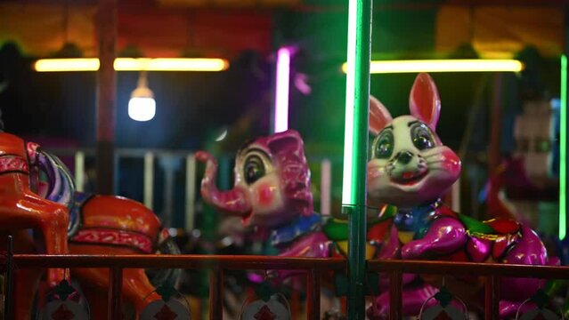 Traditional carousel running in the amusement park on the main square of a city. Close-up of beautifully decorated light, running empty seats with vivid lights. High quality